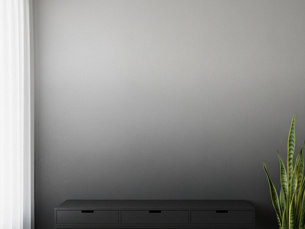 A neutral-toned, minimalist room with a snake plant in front of a gray wall and black desk.